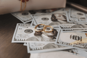 Wedding rings resting on U.S. currency representing financial considerations in a high-asset divorce